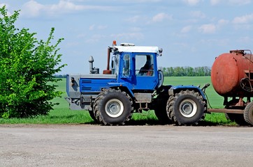 Blue tractor on road on green field background