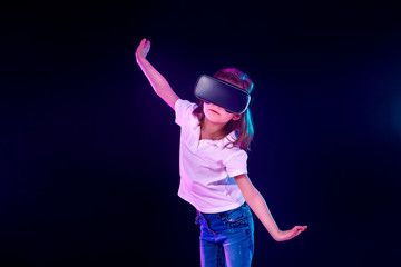 Girl 7 y.o. experiencing VR headset game on colorful background. Child using a gaming gadget for virtual reality. Futuristic goggles at young age. Virtual technology © zamuruev