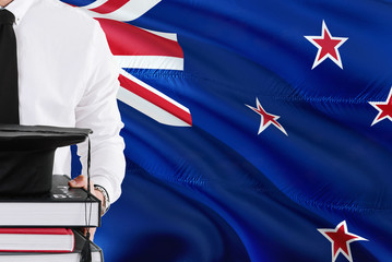 Successful student education concept. Holding books and graduation cap over New Zealand flag background.