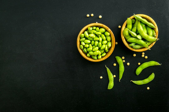vegan food with green soybeans or edamame on black background top view copy space