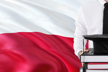 Successful Polish student education concept. Holding books and graduation cap over Poland flag...