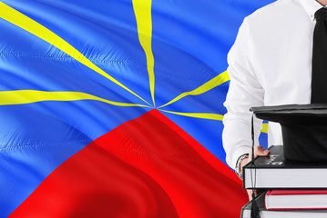 Successful student education concept. Holding books and graduation cap over Reunion flag background.