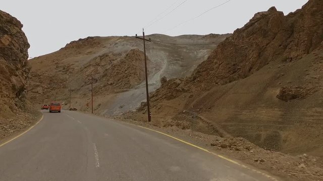 View looking forward out of a car driving down a mountain road beside a river, with tall canyon walls jutting up on either side
