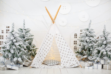 White stylish interior with little Christmas tree trees and children play wigwam 