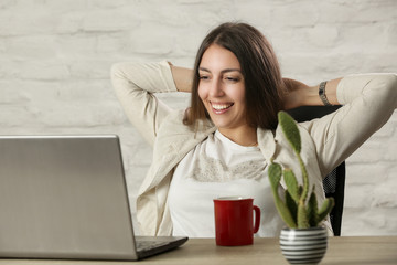 Beautiful young woman sitting at office desk in front of the laptop