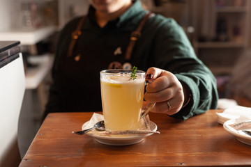 Female barista is holding a cup of hot herbal tea with a hand