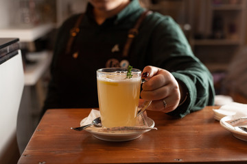 Female barista is holding a cup of hot herbal tea with a hand
