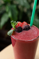 Strawberry smoothie with berries on a tropical green background