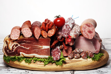 cold meat assortment with delicious salami and  fresh herbs . Variety of meat products including proscuitto, jamon  and sausages