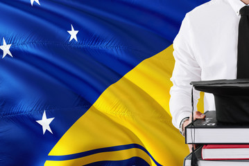 Successful student education concept. Holding books and graduation cap over Tokelau flag background.