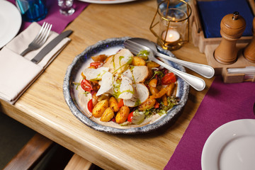 Golden-crust baked potato with sliced chicken fillet on a rustic-style plate
