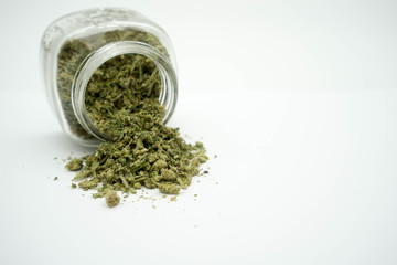Ground marijuana spilling out of a jar on a white isolated background