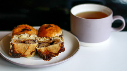 Banana chocolate pastry (bolen) and a cup of tea on black background. 