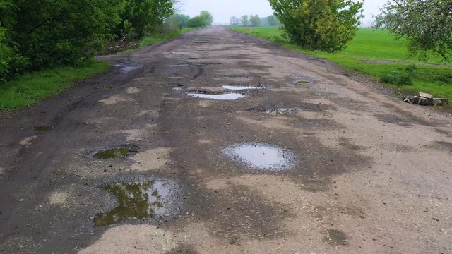 bad rural road with the lot of pits holes and puddles after the rain