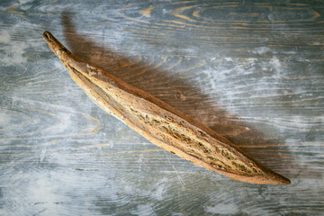 Traditional French baguette, a ficelle flute type, a thin version with seeds and grains, on display on a rustic wooden table. Baguette is one of the most iconic breads of France