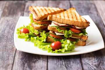 Sandwich with cheese, tomato, cucumber, sausage and salad on wooden background. Horizontal orientation