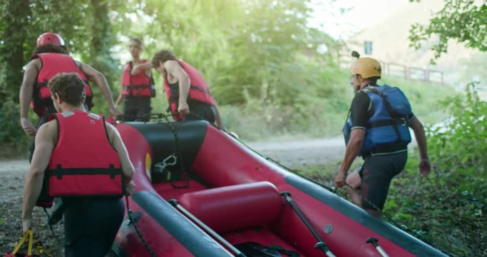 Group of people bringing raft boat after rafting on river during sunset or sunrise. Warm back light. Friends italian trip in Umbria.4k slow motion