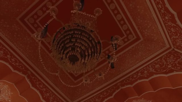 Handheld, twisting, interior shot of birds sitting on a chandelier and multiple rooms.