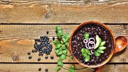 thick black bean soup or stew. Latin American or Mexican cuisine. stewed black beans served with avocado and red onion and cilantro. place for text. top view.