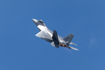 F-22 Raptor in beautiful light, with afterburners on and condensation trails forming  at the wing tips