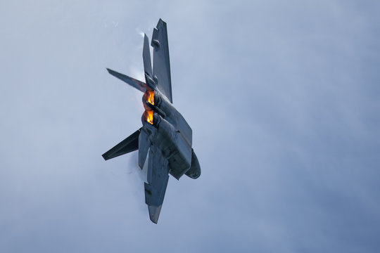 Very close tail  view of a F-22 Raptor, with afterburners on  and condensation trails around the wings