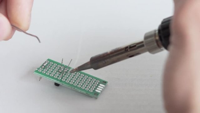 Close op of male person soldering electronic components on a self made circuit board.