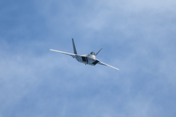 Fototapeta na wymiar Unusual frontal view of a F-22 Raptor against clouds