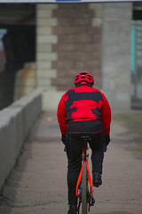 Cyclist in a red tracksuit rides along the embankment 