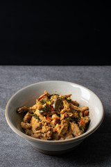 Fried stir basil with chicken internal organs in gray bowl on concrete table.