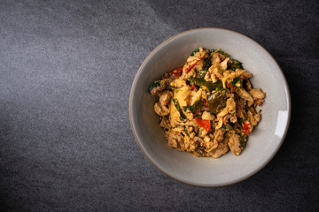 Fried stir basil with chicken internal organs in gray bowl on concrete table.