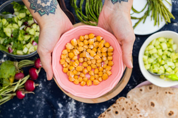 Woman hands holds cooked chickpea beans in a bowl. Vegan food. Vegetarian food.