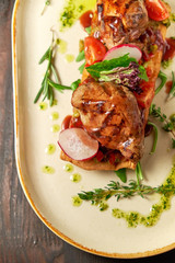 Grilled meat on pita bread on a bright oval plate. Dark wooden background. Restaurant menu