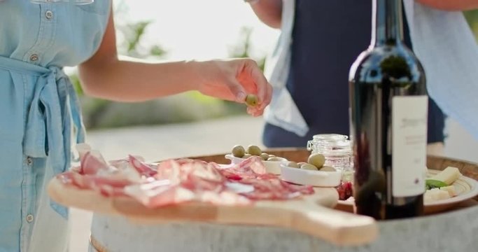Romantic couple, man and woman toasting with red wine and eating finger food appetizer at warm sunset.Food detail shot. Friends italian trip in Umbria.4k slow motion