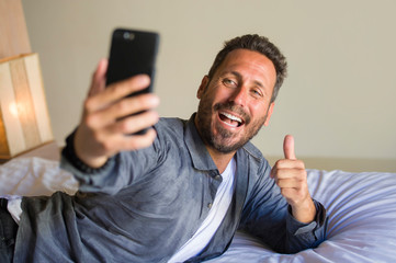 lifestyle portrait of young attractive and happy 30s or 40s man taking selfie picture with mobile...