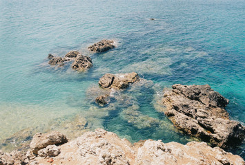 The clear water ocean. See a stone in the water.