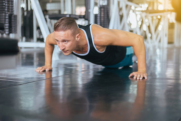 Fototapeta na wymiar Active strong man doing push up and exercises on floor at gym