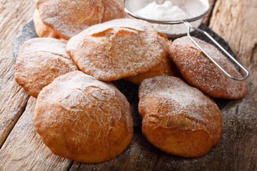 Naklejka premium Pupular street food Bunuelos sprinkled with powdered sugar close-up. horizontal