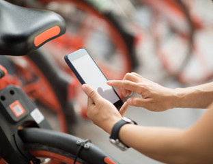 Hands using smartphone scanning the QR code of shared bike in city