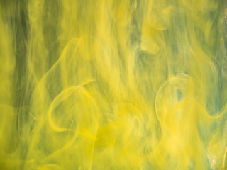 Acrylic yellow smoke swirling under water, abstract background. Close up view. Blurred background....