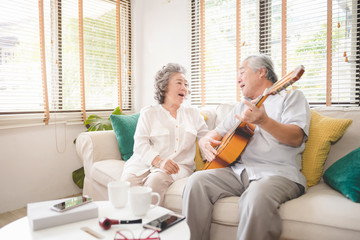 Obraz premium Meaningful moments. Lover senior couple sing a song together. Husband playing a guitar and wife is singing.