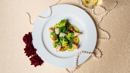 Salad of shrimps and vegetables on a white plate in the interiors of the restaurant top view.