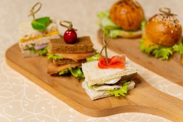 Fototapeta na wymiar Close-up of small sandwiches and hamburgers on chopping boards in restaurant interiors.