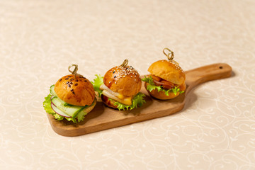 Mini hamburgers on a cutting board in the interiors of the restaurant close-up. Cold snacks menu.