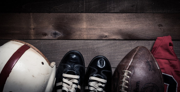 A group of vintage American football equipment on an aged wood background with copy space