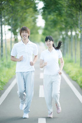 一本道でジョギングをするカップル