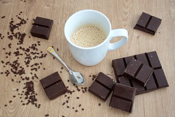 Cup of coffee and chocolate pieces on the wooden table