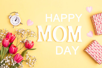 Fototapeta na wymiar Mothers day message with tulips and gifts on yellow background.