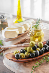 aged brie cheese on a White dish with olives and Provence herbs wooden table