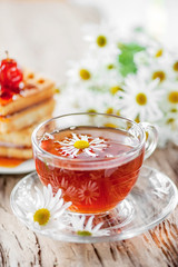 A clear Cup of medicinal chamomile tea on an old wooden table. Health and healthy lifestyle concept