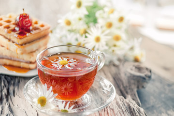 A clear Cup of medicinal chamomile tea on an old wooden table. Health and healthy lifestyle concept.